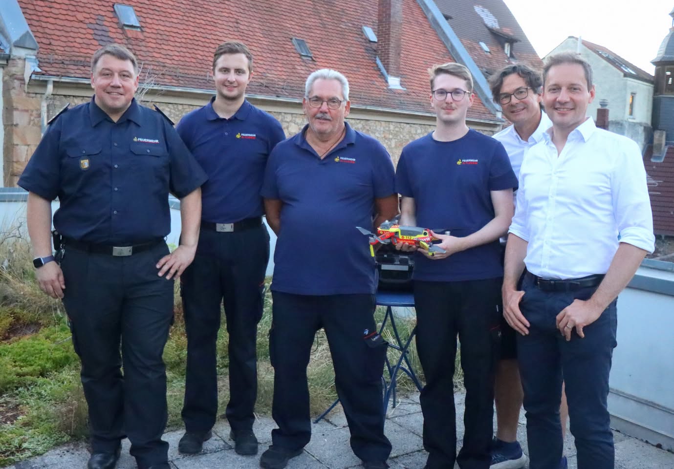 Sechs Projektbeteiligte von Feuerwehr, Stadt und L&I stehen mit der Feuerwehrdrohne zusammen